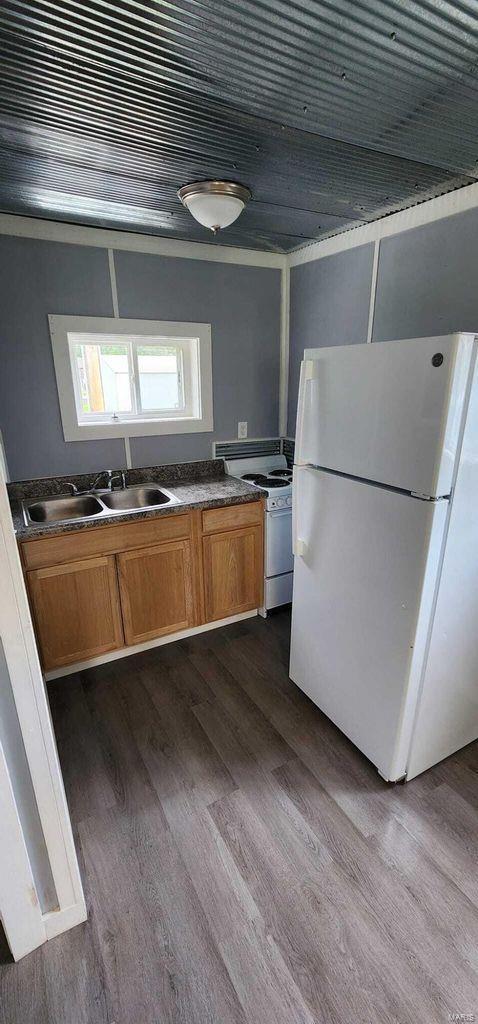 kitchen with white appliances, dark wood-type flooring, a sink, and brown cabinetry