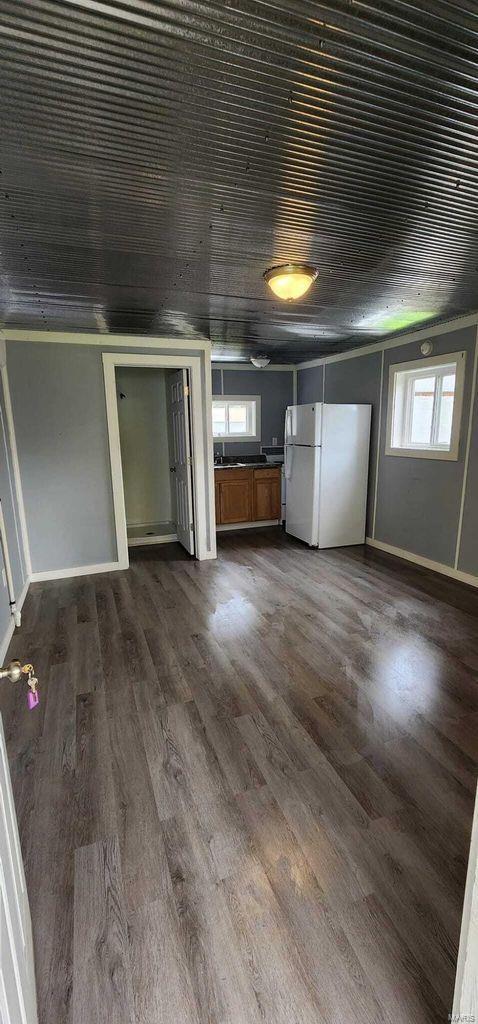 unfurnished bedroom with freestanding refrigerator, multiple windows, dark wood-style flooring, baseboards, and wood ceiling