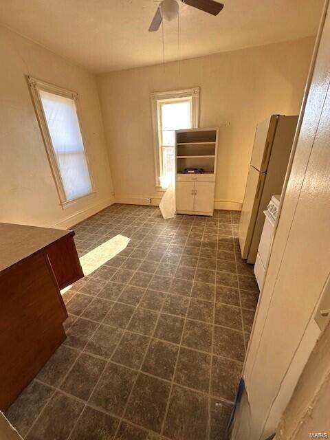 unfurnished dining area with a ceiling fan and baseboards