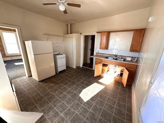 kitchen featuring white appliances, a sink, a ceiling fan, light countertops, and brown cabinets