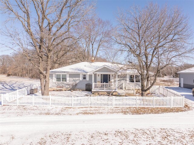 ranch-style home featuring a porch and a fenced front yard