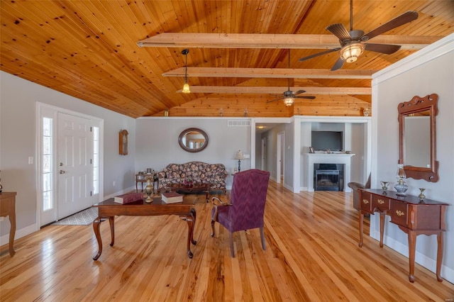 living room featuring wooden ceiling, light wood-style flooring, a glass covered fireplace, ceiling fan, and baseboards