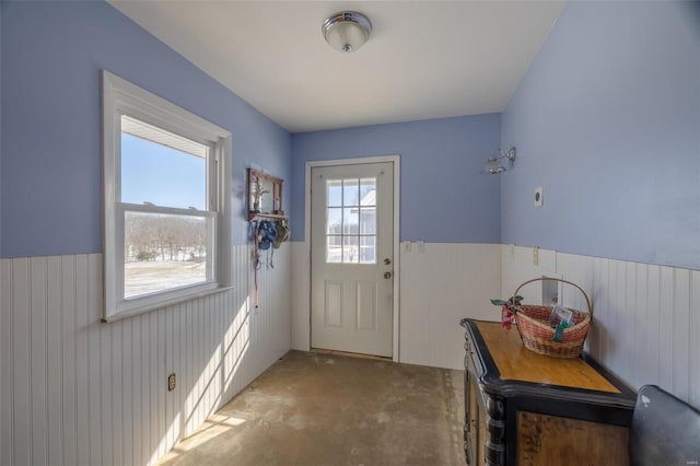 entryway featuring wainscoting, unfinished concrete floors, and wood walls