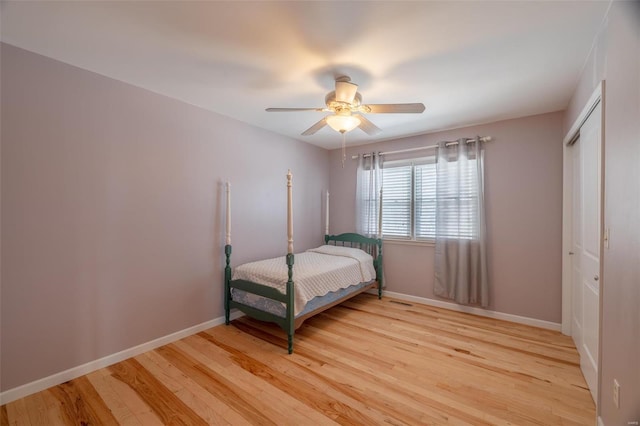 bedroom featuring light wood-style flooring, a closet, baseboards, and ceiling fan