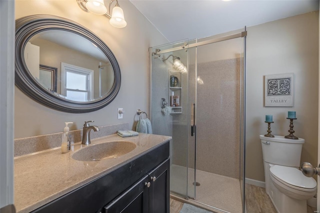 bathroom featuring a shower stall, toilet, and vanity