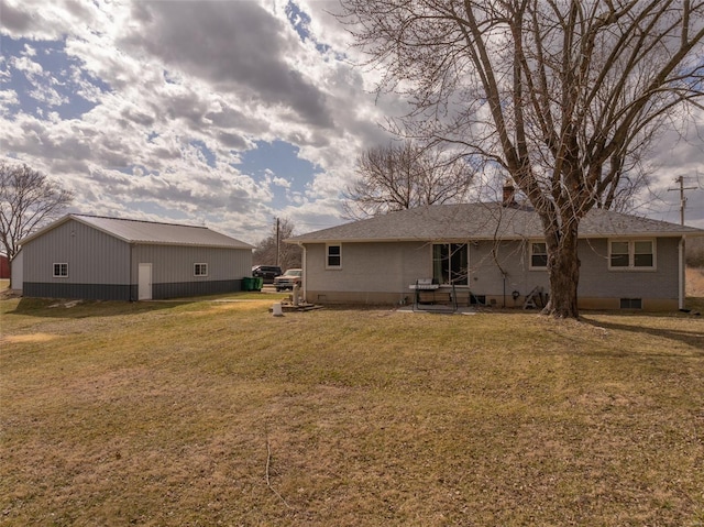 rear view of property featuring a yard and an outbuilding
