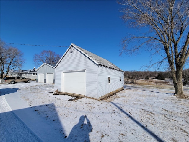view of snowy exterior with a garage and an outbuilding