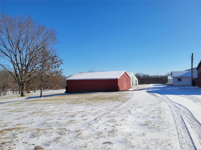 snow covered structure with a pole building and an outdoor structure