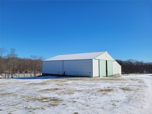 snow covered structure with a pole building and an outbuilding