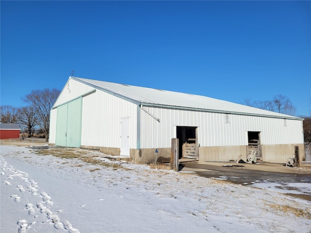 snow covered structure featuring a pole building and an outdoor structure