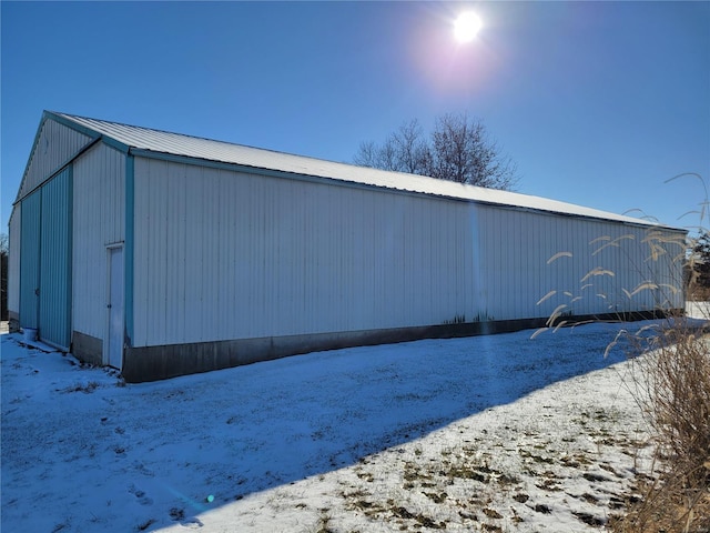 snow covered property with an outbuilding, an outdoor structure, and metal roof