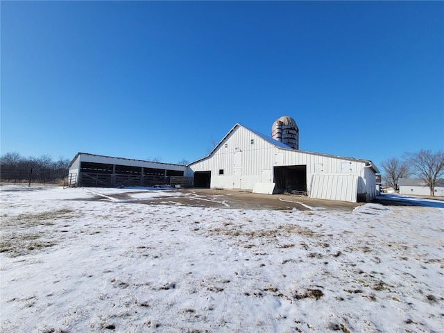 snow covered structure with an outbuilding