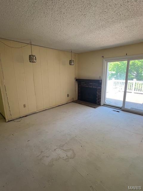 1211 Dorne Dr, Manchester, MO 63021 - unfurnished living room featuring a fireplace, a textured ceiling, and concrete floors
