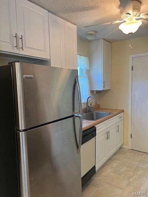 1211 Dorne Dr, Manchester, MO 63021 - kitchen featuring freestanding refrigerator, white dishwasher, white cabinetry, a ceiling fan, and a textured ceiling