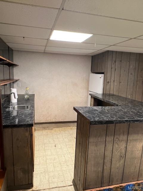 1211 Dorne Dr, Manchester, MO 63021 - kitchen featuring a paneled ceiling, freestanding refrigerator, light flooring, wood walls, and open shelves