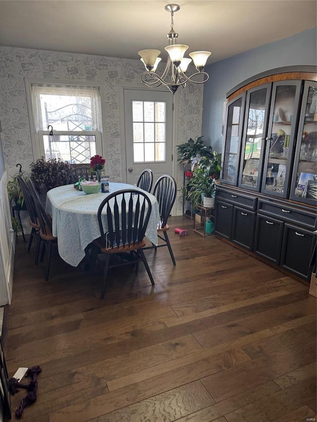 dining area featuring dark wood-style flooring, a chandelier, and wallpapered walls