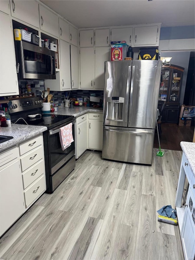 kitchen featuring stainless steel appliances, light wood finished floors, light countertops, and decorative backsplash