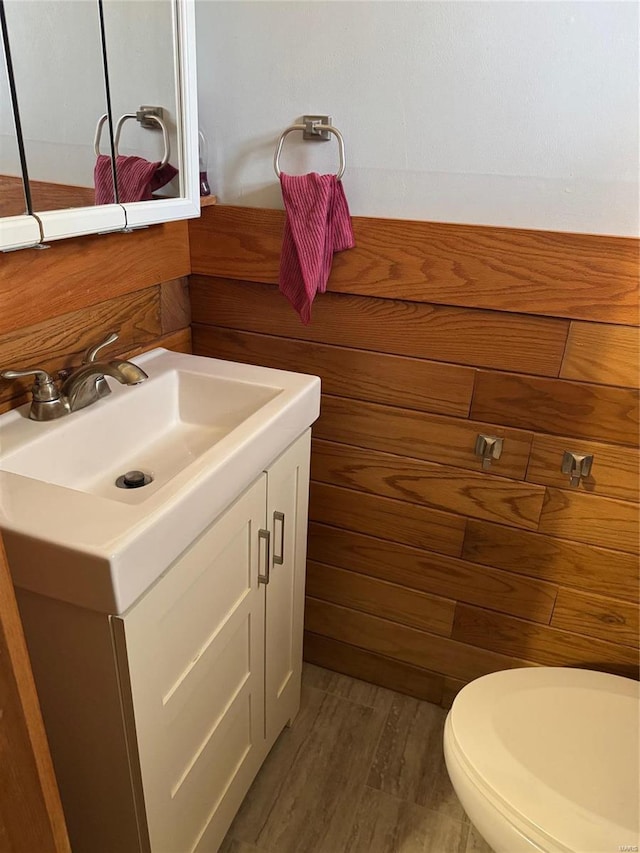 half bathroom featuring vanity, wood finished floors, and toilet