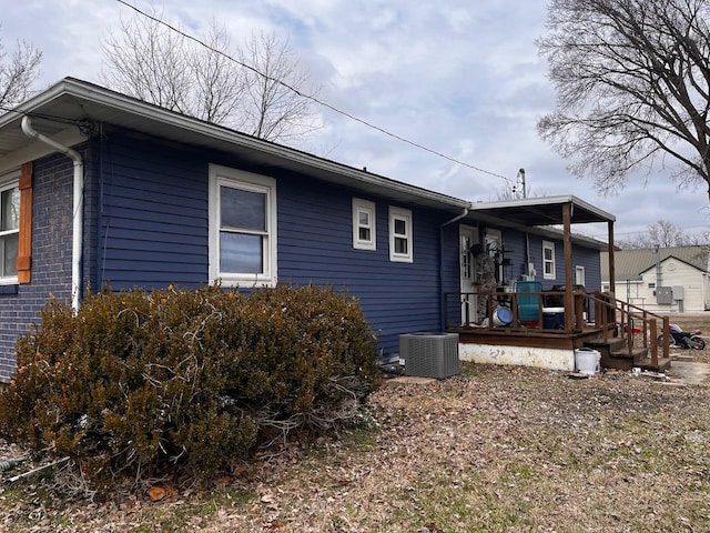 view of side of home with central air condition unit, brick siding, and a deck