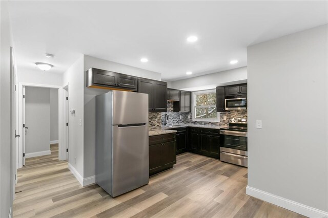 1686 Mowbry Ln, Saint Louis, MO 63136 - kitchen featuring appliances with stainless steel finishes, light wood finished floors, decorative backsplash, light stone countertops, and recessed lighting
