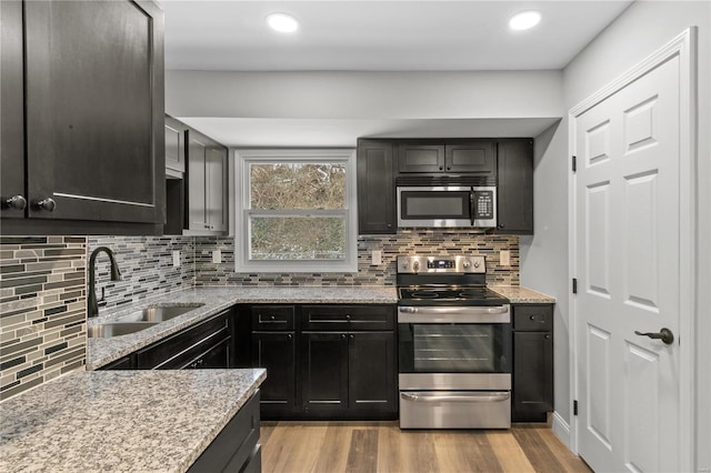 1686 Mowbry Ln, Saint Louis, MO 63136 - kitchen featuring stainless steel appliances, a sink, light stone counters, tasteful backsplash, and recessed lighting