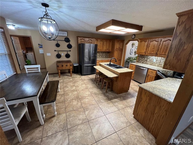 kitchen featuring freestanding refrigerator, stainless steel dishwasher, a sink, washing machine and clothes dryer, and tasteful backsplash