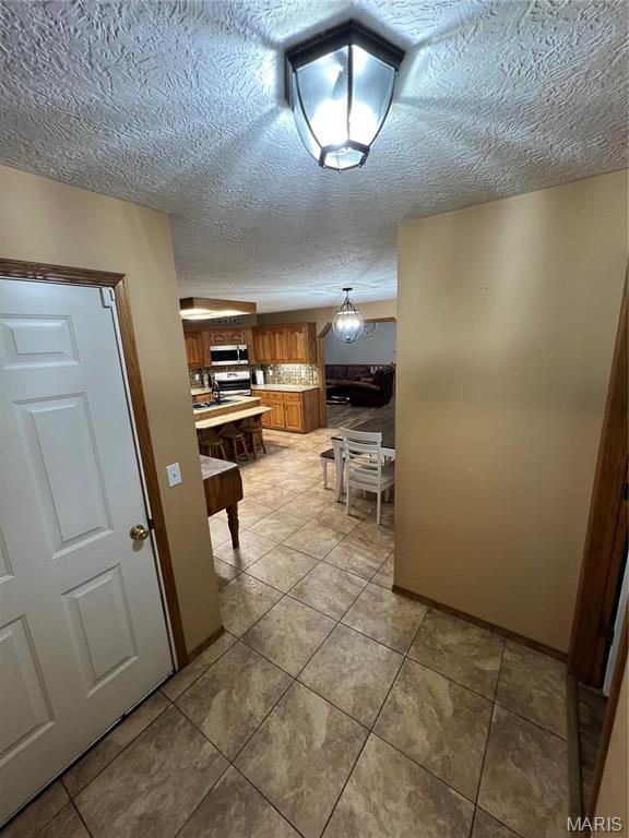 hallway with a textured ceiling and light tile patterned flooring