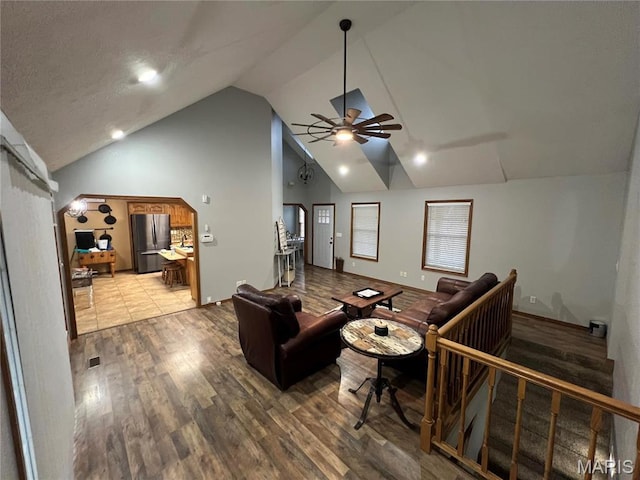 living room with lofted ceiling, ceiling fan, wood finished floors, and baseboards
