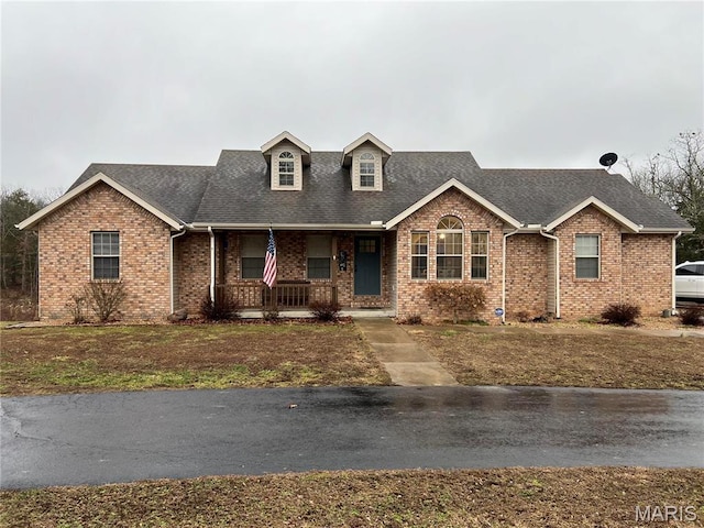 view of front of house featuring a porch, brick siding, and roof with shingles
