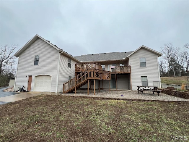 back of house featuring stairs, concrete driveway, a wooden deck, and an attached garage