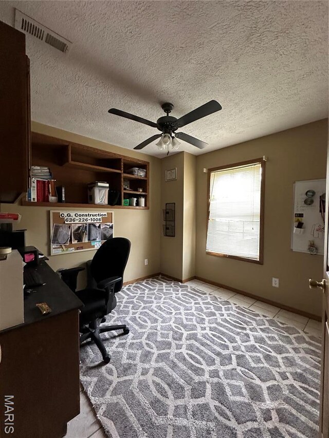 office featuring a ceiling fan, baseboards, light colored carpet, and a textured ceiling