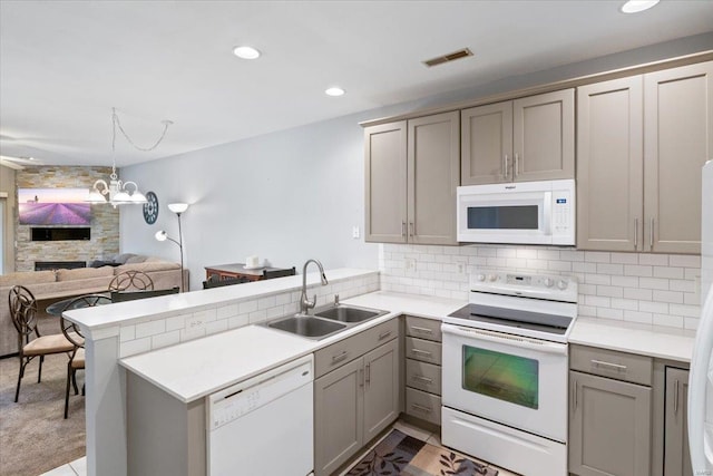 kitchen featuring white appliances, gray cabinets, a sink, a peninsula, and light countertops