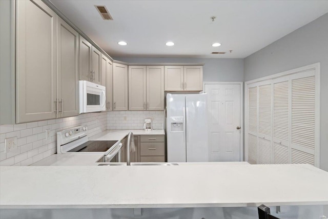 kitchen with white appliances, backsplash, light countertops, recessed lighting, and gray cabinets