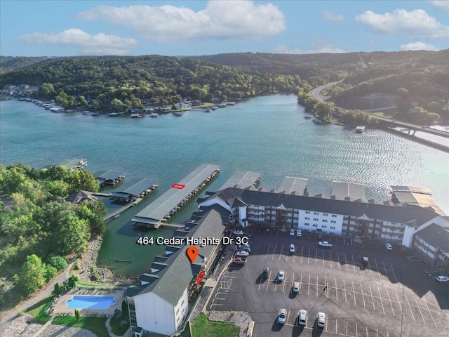 drone / aerial view of a nearby body of water and a forest