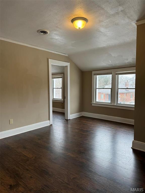 7119 Lexington Ave, Normandy, MO 63121 - spare room with a textured ceiling, baseboards, dark wood finished floors, lofted ceiling, and ornamental molding