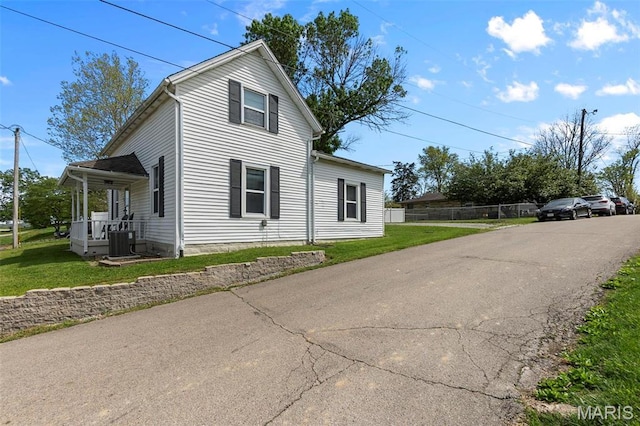 view of side of property featuring central air condition unit, a lawn, and covered porch