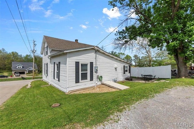 view of side of home with driveway and a shingled roof
