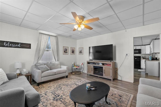 living room featuring wood finished floors, a drop ceiling, and ceiling fan