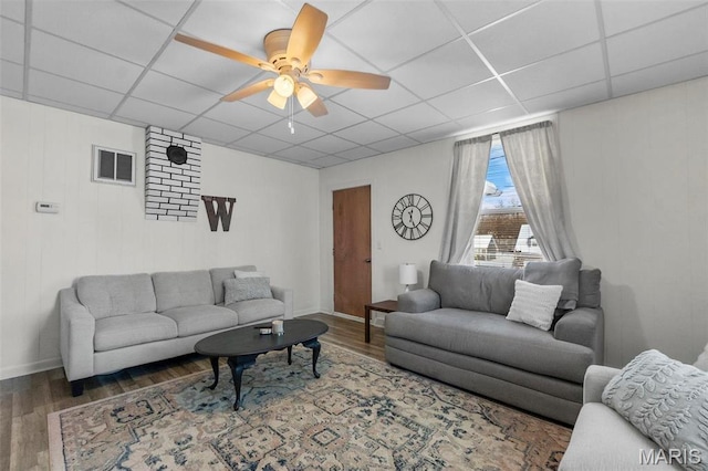 living area featuring wood finished floors, a paneled ceiling, a ceiling fan, and baseboards