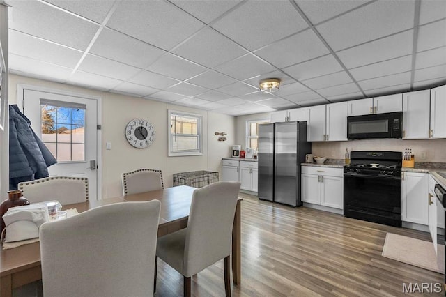 dining space with a drop ceiling and wood finished floors