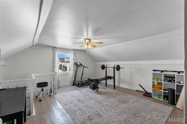 workout room featuring lofted ceiling, hardwood / wood-style flooring, a ceiling fan, and baseboards