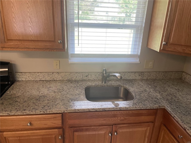 10191 Mayfair Dr, Saint Louis, MO 63136 - kitchen with a sink, healthy amount of natural light, brown cabinets, and light stone countertops