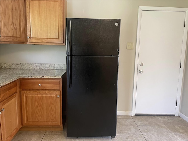10191 Mayfair Dr, Saint Louis, MO 63136 - kitchen featuring freestanding refrigerator, light tile patterned floors, baseboards, and light stone countertops