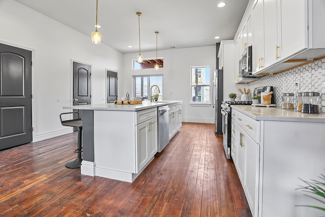 3330 Iowa Ave, Saint Louis, MO 63118 - kitchen featuring appliances with stainless steel finishes, a sink, dark wood-type flooring, white cabinets, and light countertops