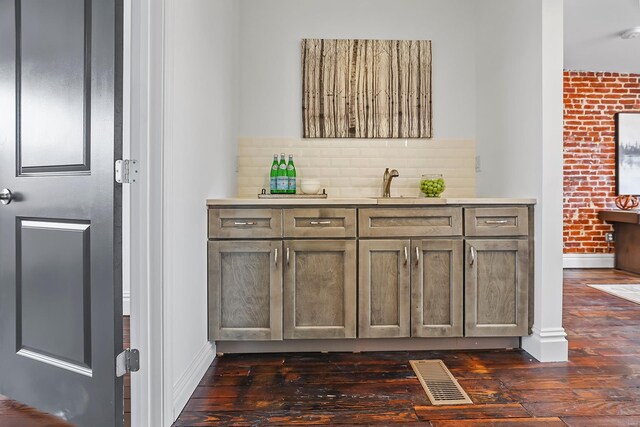 3330 Iowa Ave, Saint Louis, MO 63118 - indoor wet bar with dark wood-style floors, baseboards, and decorative backsplash