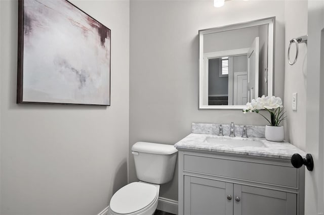 bathroom featuring toilet, baseboards, and vanity