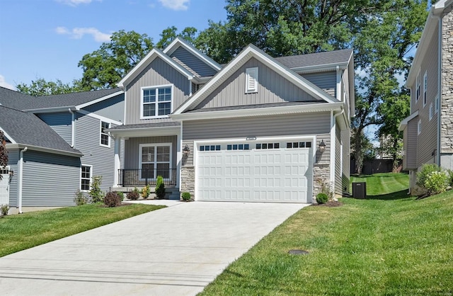 craftsman house with board and batten siding, stone siding, an attached garage, and a front lawn