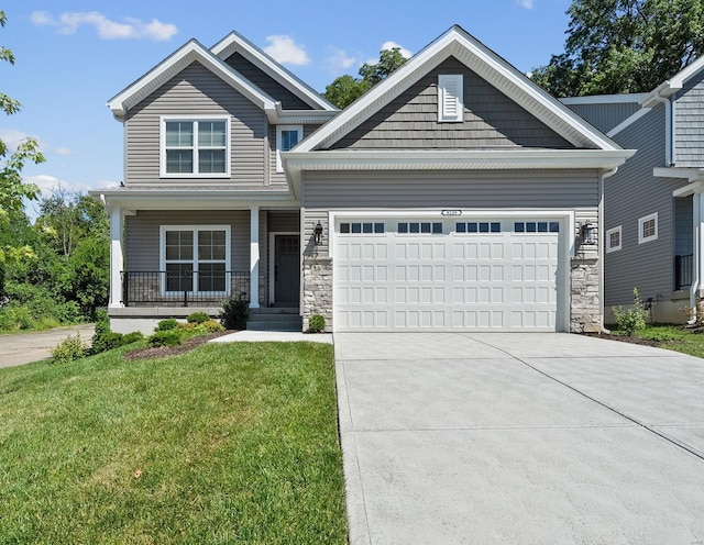 craftsman-style house with a garage, a front yard, driveway, stone siding, and covered porch