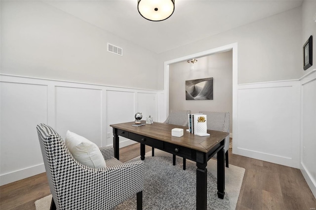office space featuring a wainscoted wall, wood finished floors, and a decorative wall