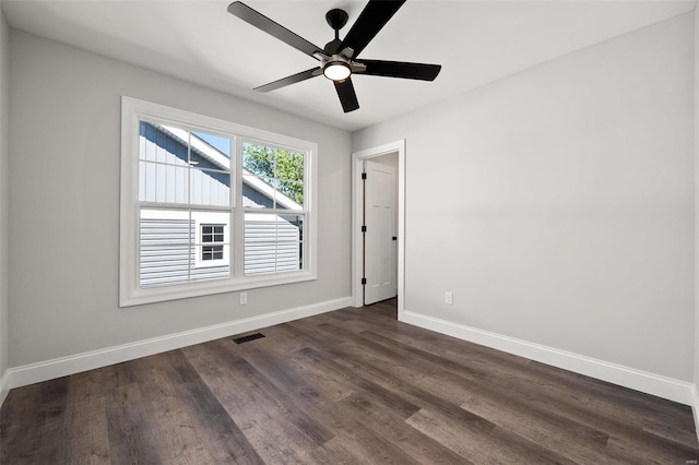 spare room featuring baseboards, a ceiling fan, and dark wood-type flooring